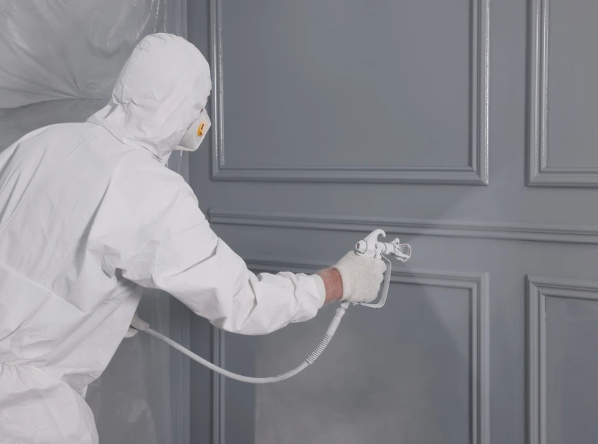 Professional painter spraying a gray garage door for a smooth finish